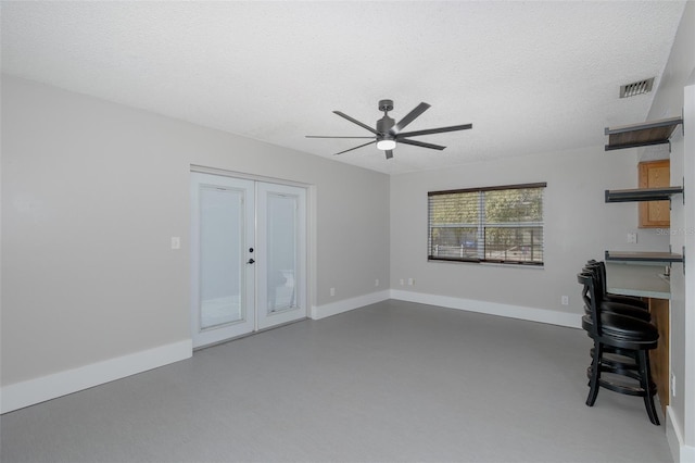 unfurnished living room featuring ceiling fan, concrete floors, a textured ceiling, and french doors