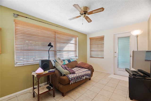 living room with ceiling fan, light tile patterned floors, and a textured ceiling