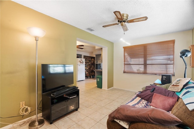 living room featuring ceiling fan, a textured ceiling, and light tile patterned flooring