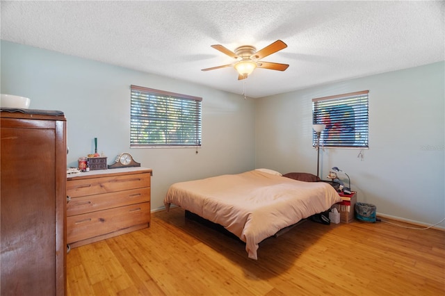 bedroom featuring ceiling fan, light hardwood / wood-style floors, and a textured ceiling