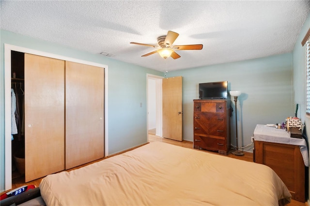 bedroom featuring ceiling fan, a textured ceiling, and a closet