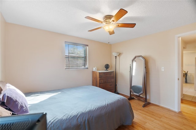 bedroom with ceiling fan, light hardwood / wood-style floors, and a textured ceiling