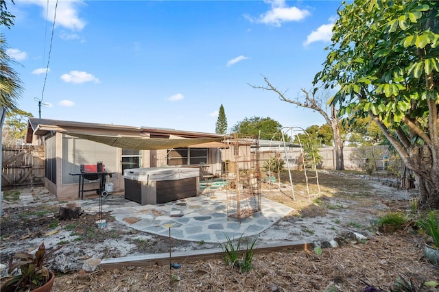 rear view of property featuring a hot tub and a patio