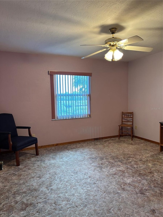 sitting room featuring ceiling fan, carpet, and a textured ceiling