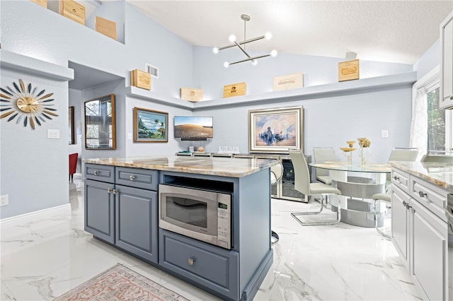 kitchen featuring a kitchen island, lofted ceiling, white cabinets, light stone countertops, and a textured ceiling