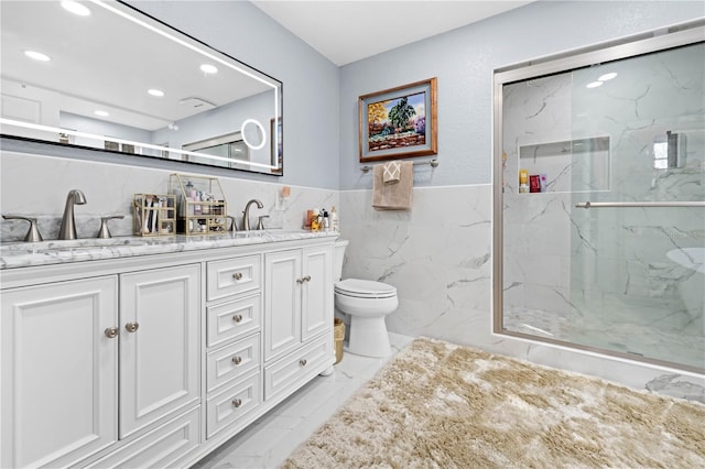 bathroom with a shower with door, vanity, tile walls, and toilet