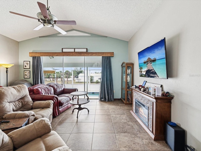 living room with lofted ceiling, ceiling fan, a textured ceiling, and light tile patterned flooring