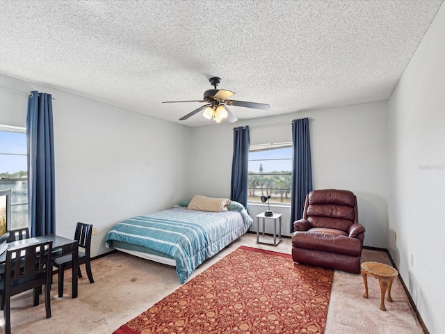 carpeted bedroom featuring ceiling fan and a textured ceiling