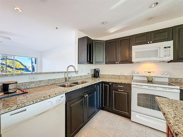 kitchen featuring sink, dark brown cabinets, light tile patterned floors, white appliances, and light stone countertops