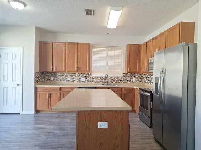 kitchen with sink, appliances with stainless steel finishes, backsplash, dark hardwood / wood-style floors, and a center island