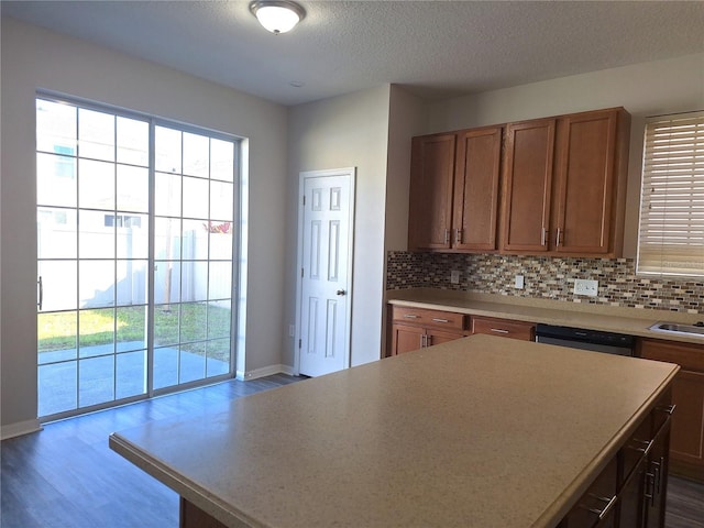 kitchen featuring wood-type flooring, a kitchen island, dishwasher, and decorative backsplash