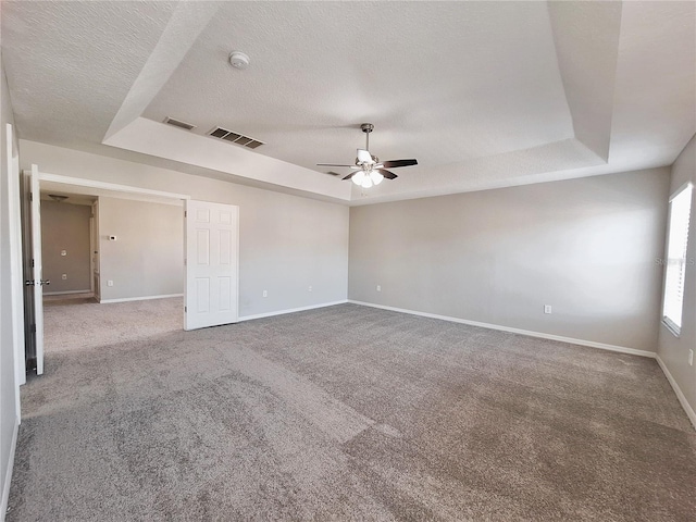 carpeted empty room with ceiling fan, a tray ceiling, and a textured ceiling