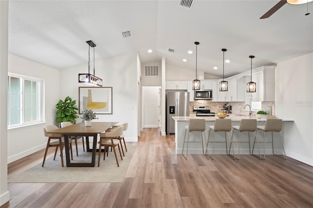 kitchen with pendant lighting, stainless steel appliances, kitchen peninsula, and white cabinets