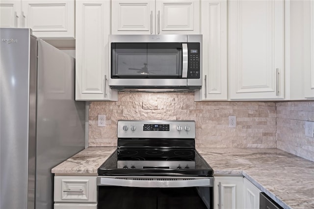 kitchen with white cabinetry, stainless steel appliances, light stone counters, and decorative backsplash