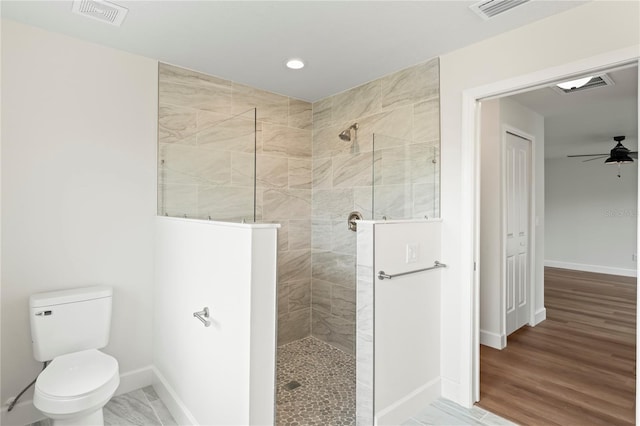 bathroom featuring hardwood / wood-style floors, a tile shower, ceiling fan, and toilet