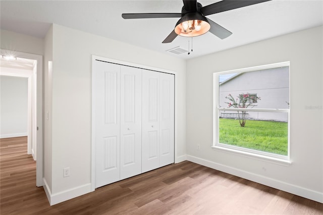 unfurnished bedroom with hardwood / wood-style floors, ceiling fan, and a closet