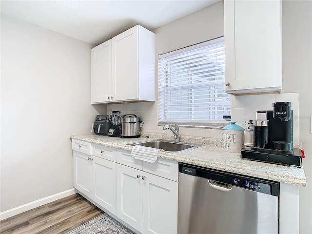 kitchen with sink, white cabinetry, light stone counters, stainless steel dishwasher, and hardwood / wood-style flooring