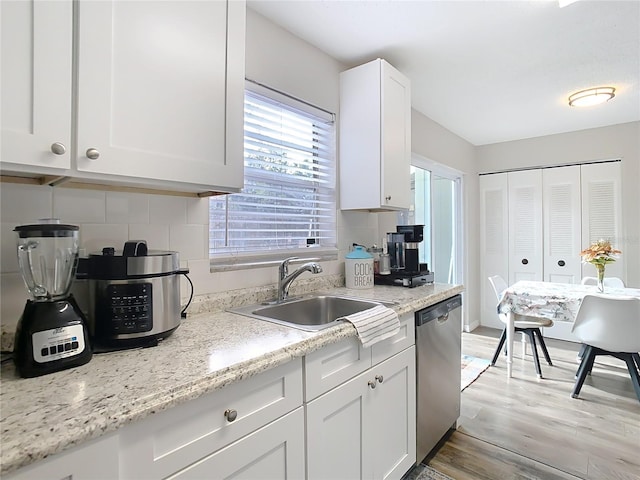 kitchen featuring tasteful backsplash, sink, stainless steel dishwasher, and white cabinets