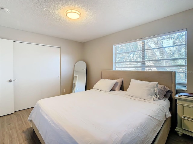 bedroom with a closet, wood-type flooring, and a textured ceiling