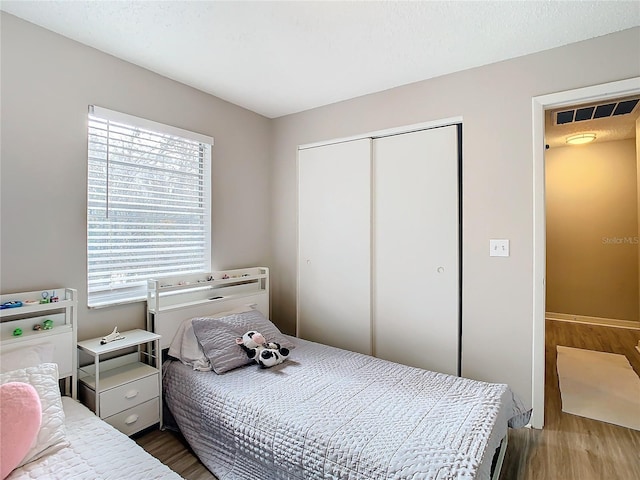 bedroom featuring hardwood / wood-style flooring, multiple windows, and a closet