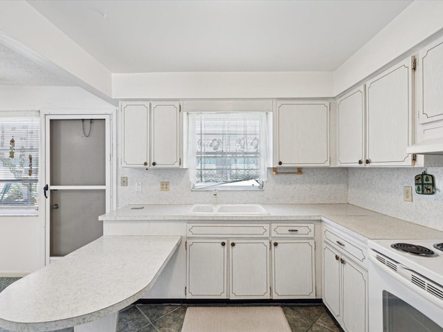 kitchen with electric range, dark tile patterned flooring, sink, and white cabinets