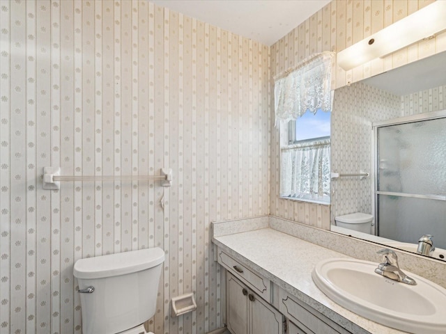 bathroom with a shower with door, vanity, and toilet