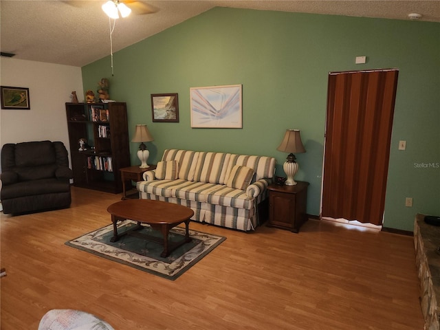 living room featuring ceiling fan, wood-type flooring, vaulted ceiling, and a textured ceiling