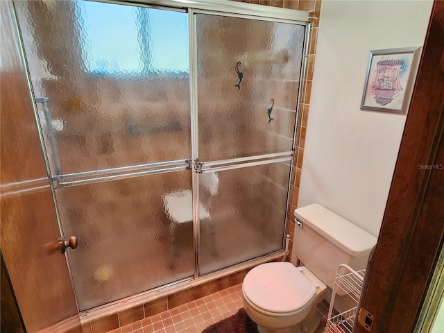 bathroom with toilet, tile patterned floors, and a shower with shower door