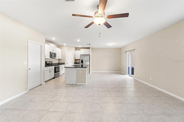 kitchen with light tile patterned floors, appliances with stainless steel finishes, a kitchen island, ceiling fan, and white cabinets