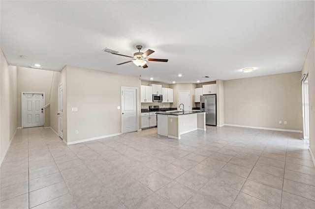 kitchen featuring appliances with stainless steel finishes, white cabinetry, sink, ceiling fan, and a center island with sink