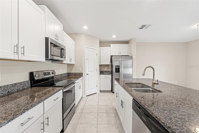 kitchen featuring appliances with stainless steel finishes, sink, dark stone counters, and white cabinets