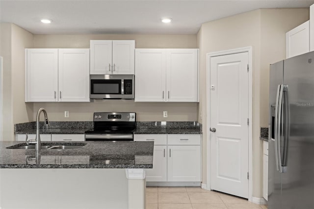 kitchen featuring sink, white cabinetry, light tile patterned floors, appliances with stainless steel finishes, and dark stone counters