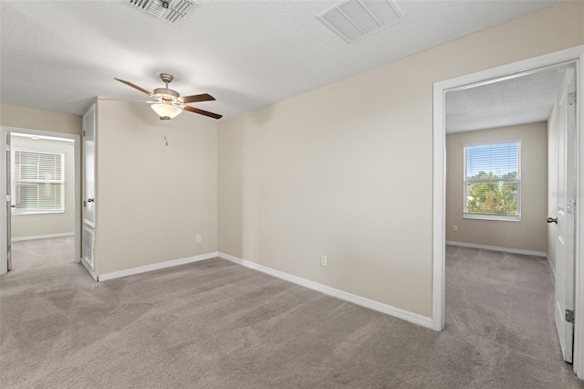 unfurnished room with light carpet, ceiling fan, and a textured ceiling