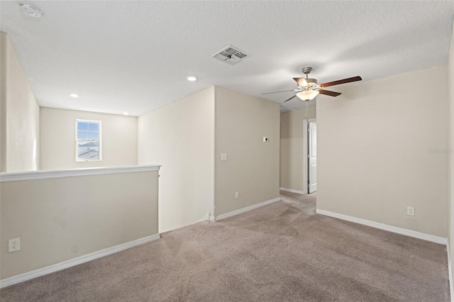 empty room featuring ceiling fan, light carpet, and a textured ceiling