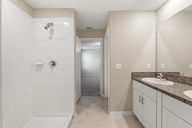 bathroom featuring tile patterned flooring, vanity, and tiled shower