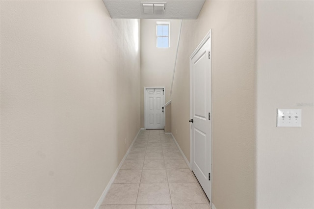 hallway with light tile patterned floors and a textured ceiling