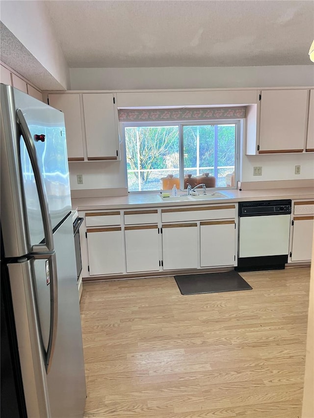 kitchen with dishwasher, sink, white cabinets, stainless steel fridge, and light hardwood / wood-style floors