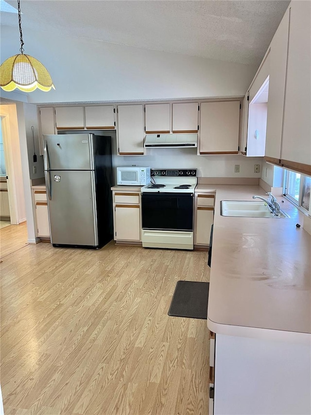 kitchen with electric stove, sink, lofted ceiling, stainless steel refrigerator, and hanging light fixtures