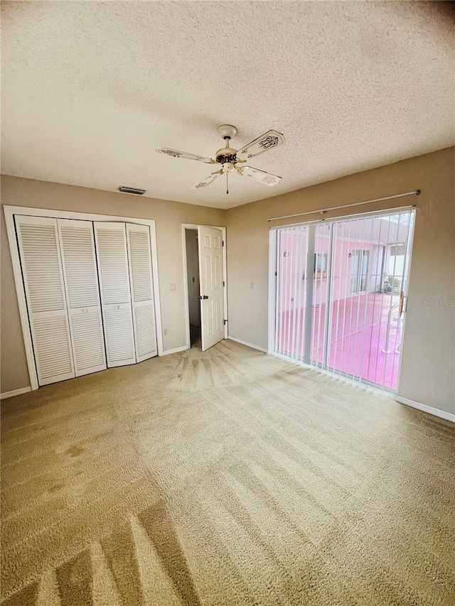 unfurnished bedroom featuring ceiling fan, a closet, a textured ceiling, and carpet