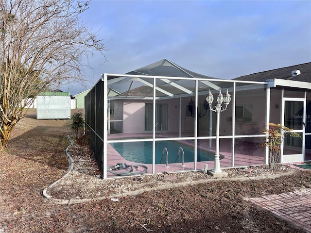 back of house with a shed, a patio area, and glass enclosure