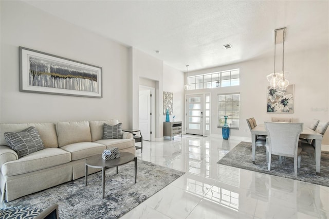 living room featuring french doors, a high ceiling, a textured ceiling, and a notable chandelier