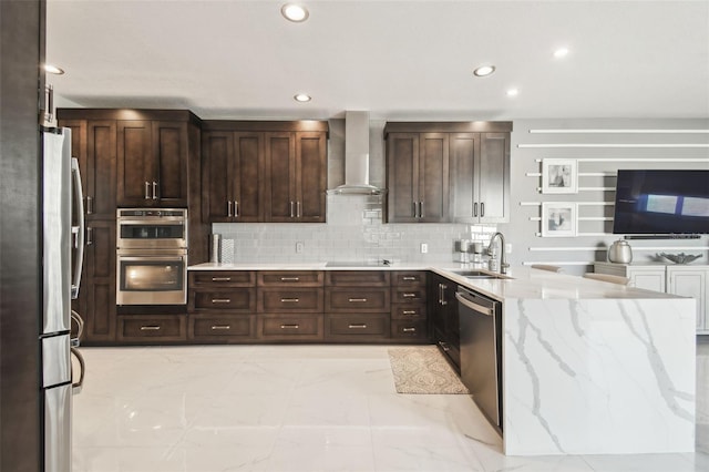 kitchen featuring wall chimney range hood, sink, appliances with stainless steel finishes, light stone countertops, and decorative backsplash