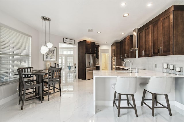 kitchen with stainless steel refrigerator with ice dispenser, decorative light fixtures, kitchen peninsula, decorative backsplash, and wall chimney range hood