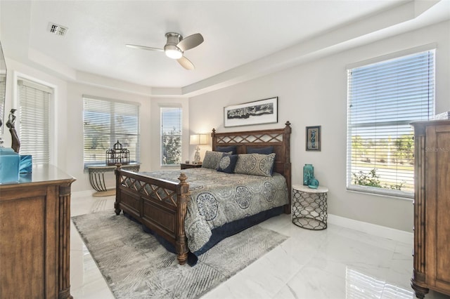 bedroom featuring ceiling fan, a tray ceiling, and multiple windows