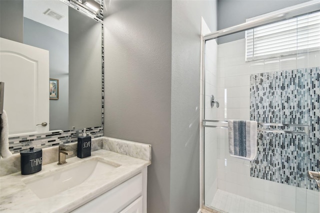 bathroom with vanity, decorative backsplash, and walk in shower