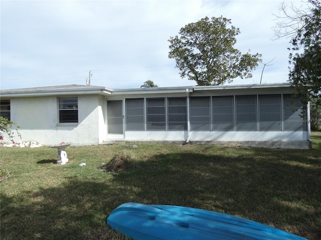 view of side of home with a sunroom and a yard