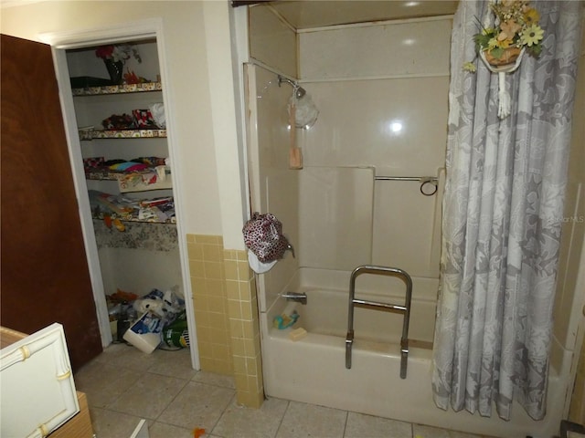 bathroom featuring shower / bathtub combination with curtain, tile patterned flooring, and tile walls