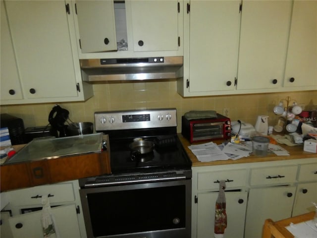 13737 Michelle Ave, Hudson, FL 34667 - kitchen featuring stainless steel electric range, under cabinet range hood, decorative backsplash, and white cabinetry