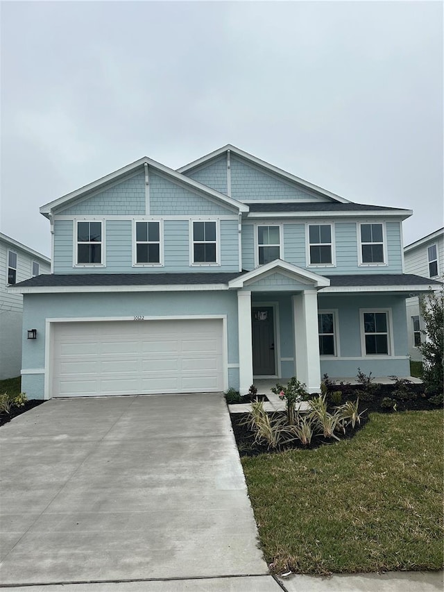 view of front of house featuring a garage, driveway, a front lawn, and stucco siding