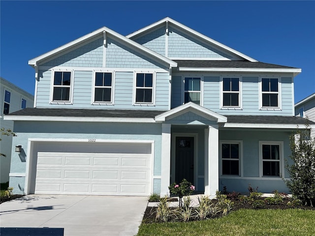 view of front facade with a shingled roof, driveway, a garage, and stucco siding